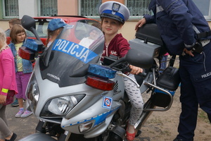 Dziewczynka w policyjnej czapce na oznakowanym motocyklu ruchu drogowego