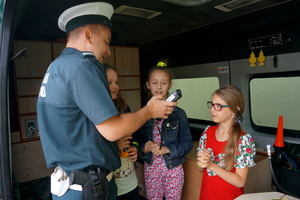Inspektor prezentuje uczniom wyposażenie radiowozu Inspekcji Transportu Drogowego