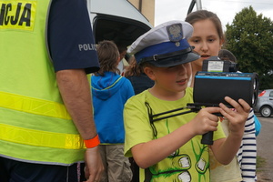 Policjant z wydziału ruchu drogowego prezentuję uczniom urządzenie do pomiaru prędkości