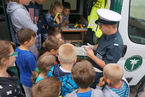 Inspektor prezentuje uczniom wyposażenie radiowozu Inspekcji Transportu Drogowego