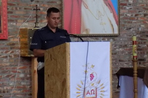 Policjant z Wydziału Ruchu Drogowego odczytuje w kościele apel promujący prowadzenie pojazdów zgodnie z zasadami ruchu drogowego.