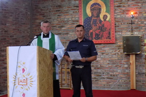 Policjant z Wydziału Ruchu Drogowego wspólnie z  ks. kanonikiem Grzegorzem Cypalskim odczytują w kościele  apel promujący prowadzenie pojazdów zgodnie z zasadami  ruchu drogowego.