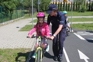 Policjantka pomaga jechać dziewczynce na rowerze