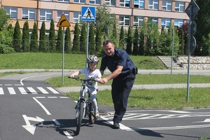 Policjant pomaga jechać dziecku na rowerze