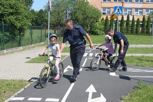 Policjanci pomagają jadącym na rowerach dzeciom