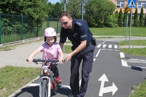 Policjant pomaga utrzymać równowagę dziewczynce na rowerze