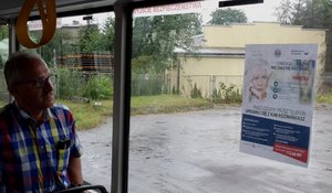 Mężczyzna patrzy na plakat umieszczony na szybie autobusu