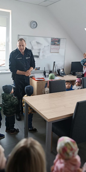 Na zdjęciu widoczny umundurowany policjant podczas spotkania z dziećmi.