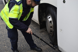 Na zdjęciu widoczny policjant sprawdzający podwozie autokaru.