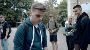 Zdjęcie ze strony www.policja.pl. Widoczny jest na nim nastolatek z podbitym okiem, który idzie przez dziedziniec szkoły. Obserwują go kpiący rówieśnicy.
